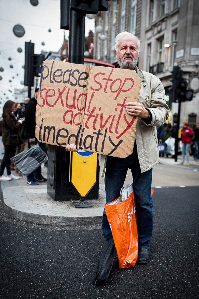 Picture of a man holding a cardboard saying "PLEASE STOP SEXUAL ACTIVITY IMEDIATELY".  London, united kingdom. 2015 © Pedro Rodrigues